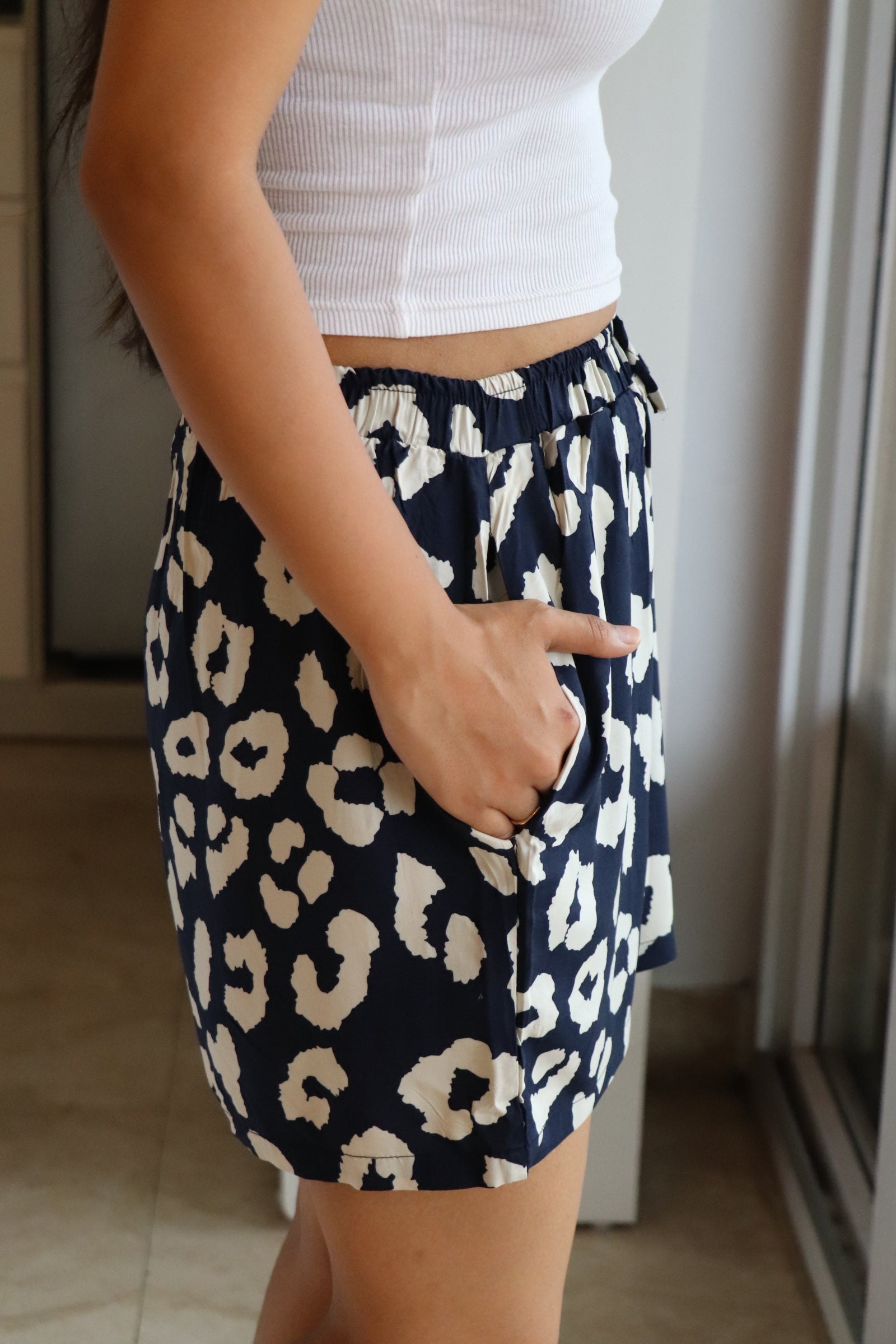 Model wearing navy abstract printed viscose shorts with elastic waistband and pockets for comfort.